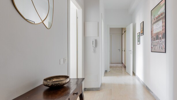 A hallway with a wooden table, a white wall, and a door leading to another room. - A Casa di Giorgia II by Wonderful Italy (Bologna)
