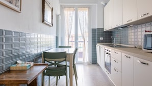 A modern kitchen with a dining area, featuring a tiled backsplash, a wooden table, and a green chair. - A Casa di Giorgia II by Wonderful Italy (Bologna)