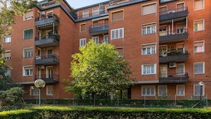 A multi-story brick building with balconies, windows, and a tree in front. - A Casa di Giorgia II by Wonderful Italy (Bologna)
