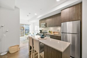 Eine moderne Küche mit Holzausbau, Edelstahlgeräten und einer zentralen Kochinsel mit Sitzgelegenheit.