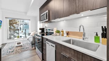 A modern kitchen with a built-in microwave, stainless steel appliances, a wooden countertop, and a large window.