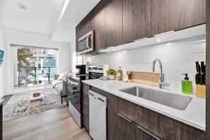 A modern kitchen with a built-in microwave, stainless steel appliances, a wooden countertop, and a large window.