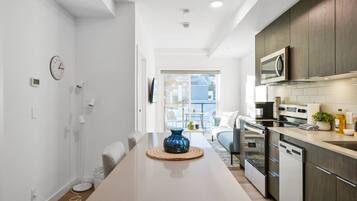 A modern kitchen with a dining area, a clock, and a view to the outside.