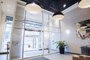 Um interior moderno com grandes portas de vidro, uma planta em vaso e iluminação pendente.