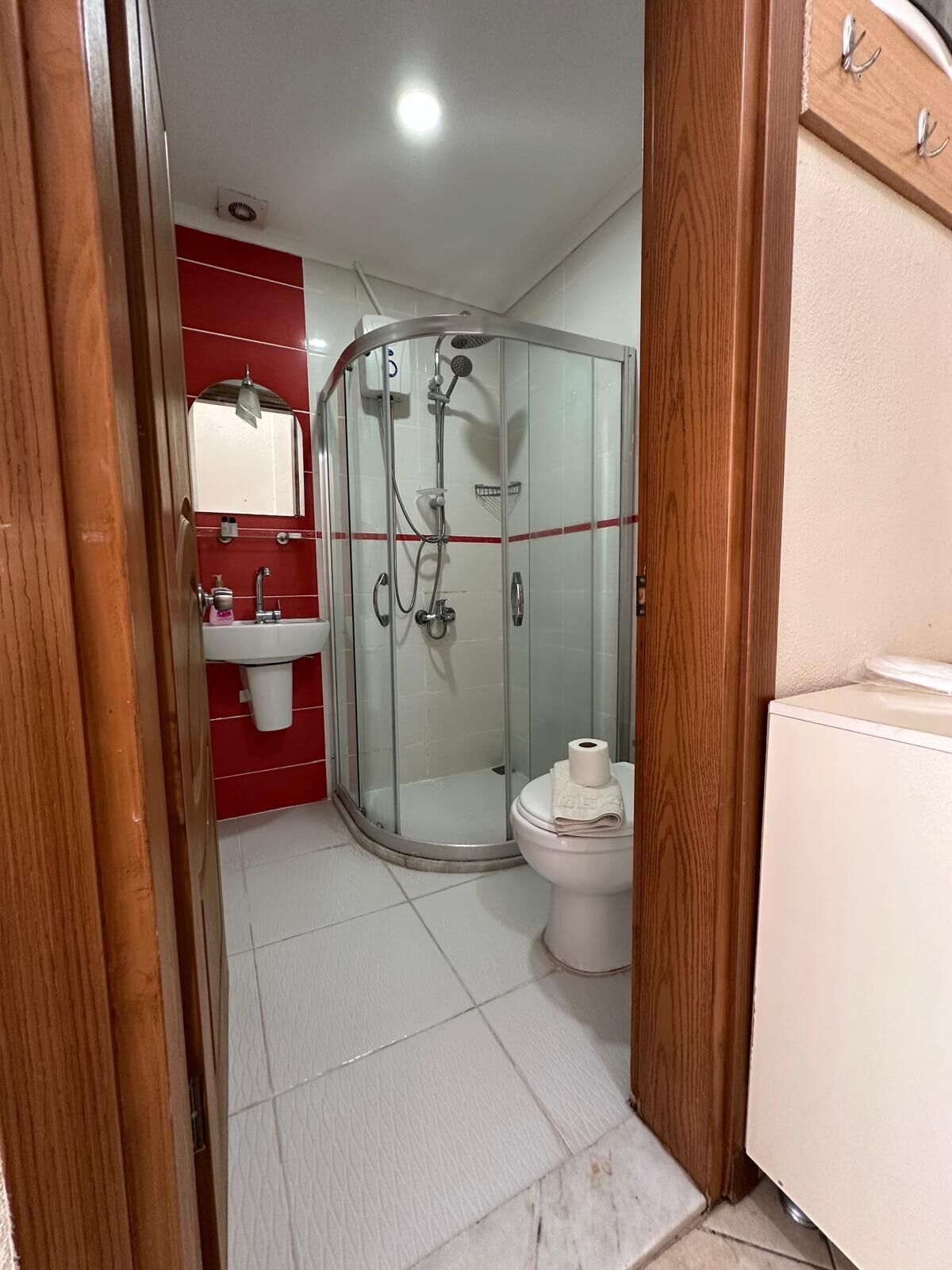 A bathroom with a glass-enclosed shower, a toilet, and a sink with a mirror.