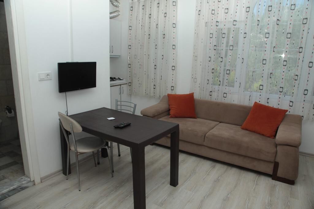 A living room with a sofa, a table, and a TV mounted on the wall.