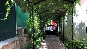 A covered pathway lined with potted plants and a brick wall on one side. - Kampüs Garden (Fethiye)