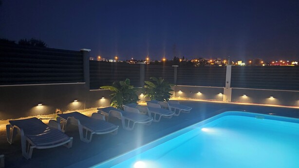 Una piscina con sillas de descanso e iluminación ambiental.