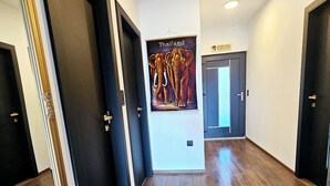 Un pasillo con suelo de madera, puertas oscuras y un cartel con elefantes que dice "Thailand".