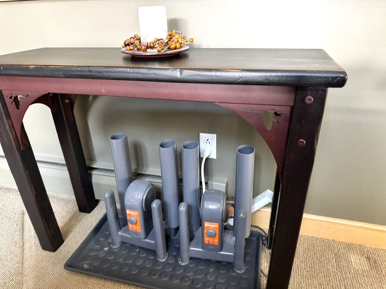 A table with a black top and a red underside, featuring a power strip with multiple plugs and a plate of dried fruits on top.