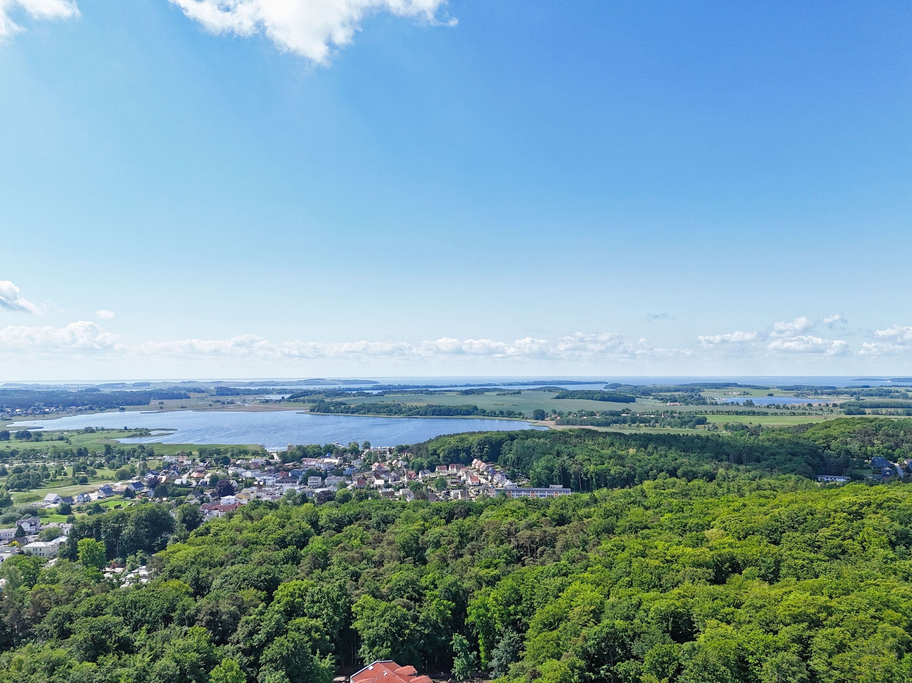 Une ville nichée dans une vallée, avec un lac et des collines boisées en arrière-plan.