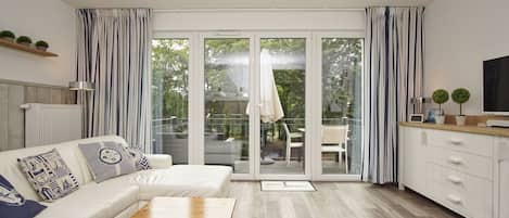 A modern living room with a sofa, coffee table, and a sliding glass door leading to an outdoor patio.