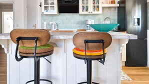 A modern kitchen with two bar stools, a refrigerator, and pendant lighting. - Vacation at the Baltic Sea - Strandresidenz Lehrer Lämpel FeWo Anna Mari (Glowe)