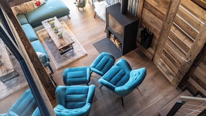 Un salon moderne avec une cheminée, des fauteuils bleus, un canapé et une table basse.