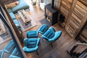 A modern living room with a fireplace, blue armchairs, a sofa, and a coffee table.