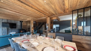 Un espace repas moderne avec un plafond en bois, une cheminée et une vue sur la cuisine.