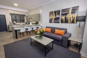 Una sala de estar moderna con un sofá gris, una mesa de centro y un comedor con sillas.