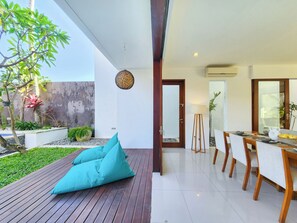 Un área de comedor al aire libre moderna con una terraza de madera, una mesa con sillas y una planta en maceta.