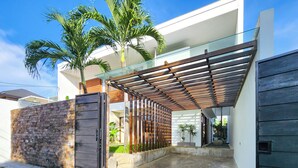A modern house with a gated entrance, a covered patio area, and a stone wall.
