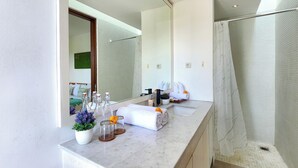A modern bathroom with a large mirror, a shower enclosure, and a marble countertop with toiletries. - Villa Abigail Seminyak by Nagisa Bali (Kerobokan)