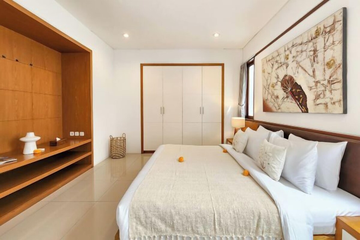Un dormitorio moderno con una cama grande, un armario de madera, una obra de arte en la pared y una mesita de noche.