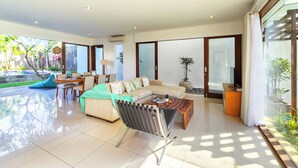 A spacious living area with a sofa, coffee table, and a dining table set up.