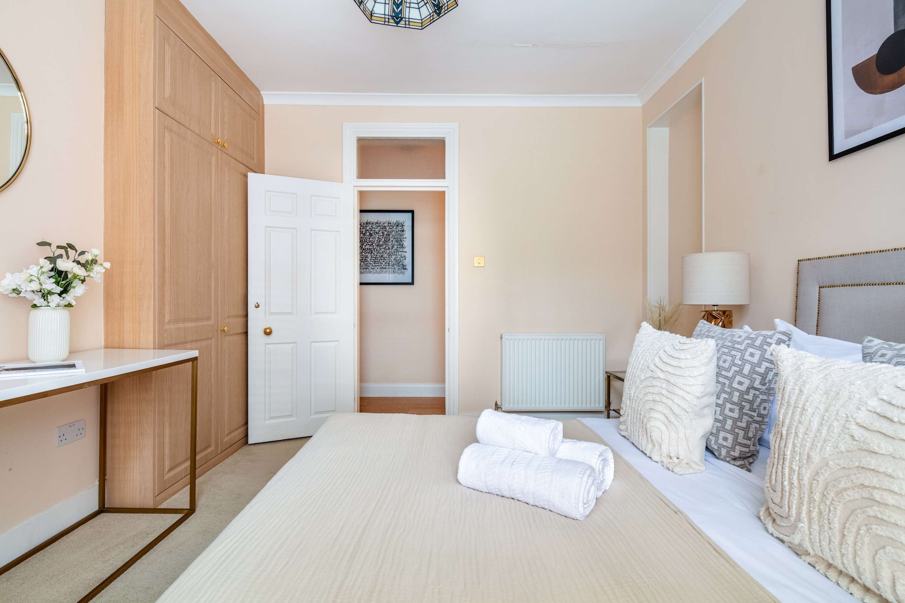 A bedroom with a bed, bedside table, lamp, and a wardrobe.