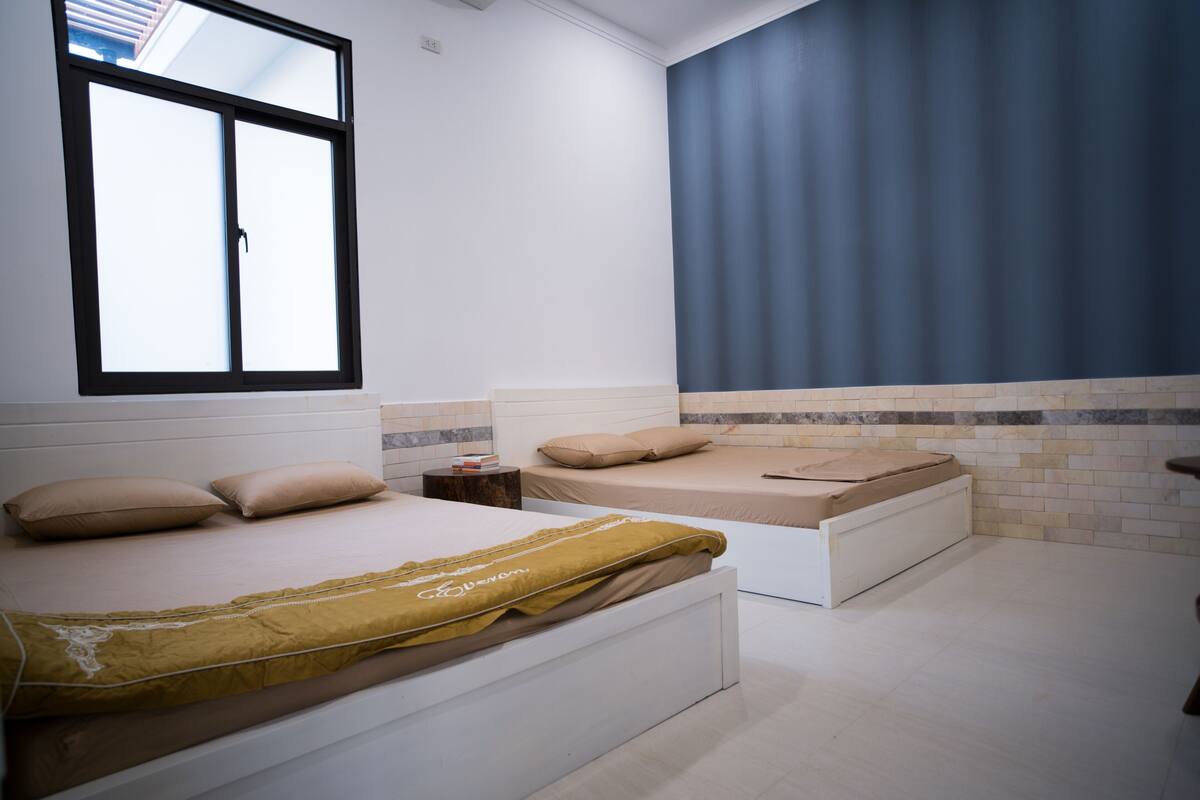 Un dormitorio con dos camas, una ventana y una cortina azul.
