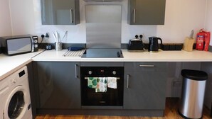 A compact kitchen with a microwave, toaster, kettle, and oven. - 4 Bedroom, Newly Refurbished Home in East Kilbride (East Kilbride)