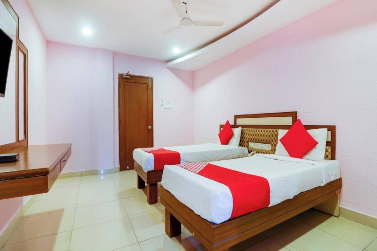 A hotel room with two wooden beds, a wooden desk, and a ceiling fan.