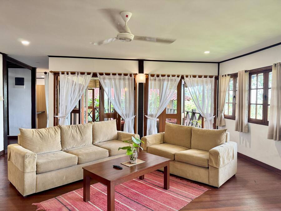 A living room with two beige sofas, a wooden coffee table, and a ceiling fan.