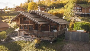 Une cabane en bois dotée d’un balcon, entourée d’un paysage vallonné.
