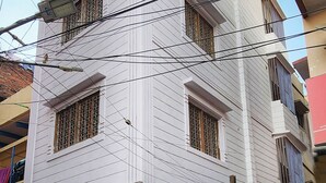 Un edificio de varios pisos con ventanas protegidas por barrotes y una línea eléctrica a la vista.