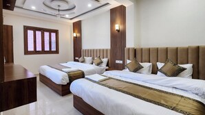 Habitación de hotel con dos camas, cabecero de madera, ventana grande con vidrieras y ventilador de techo.
