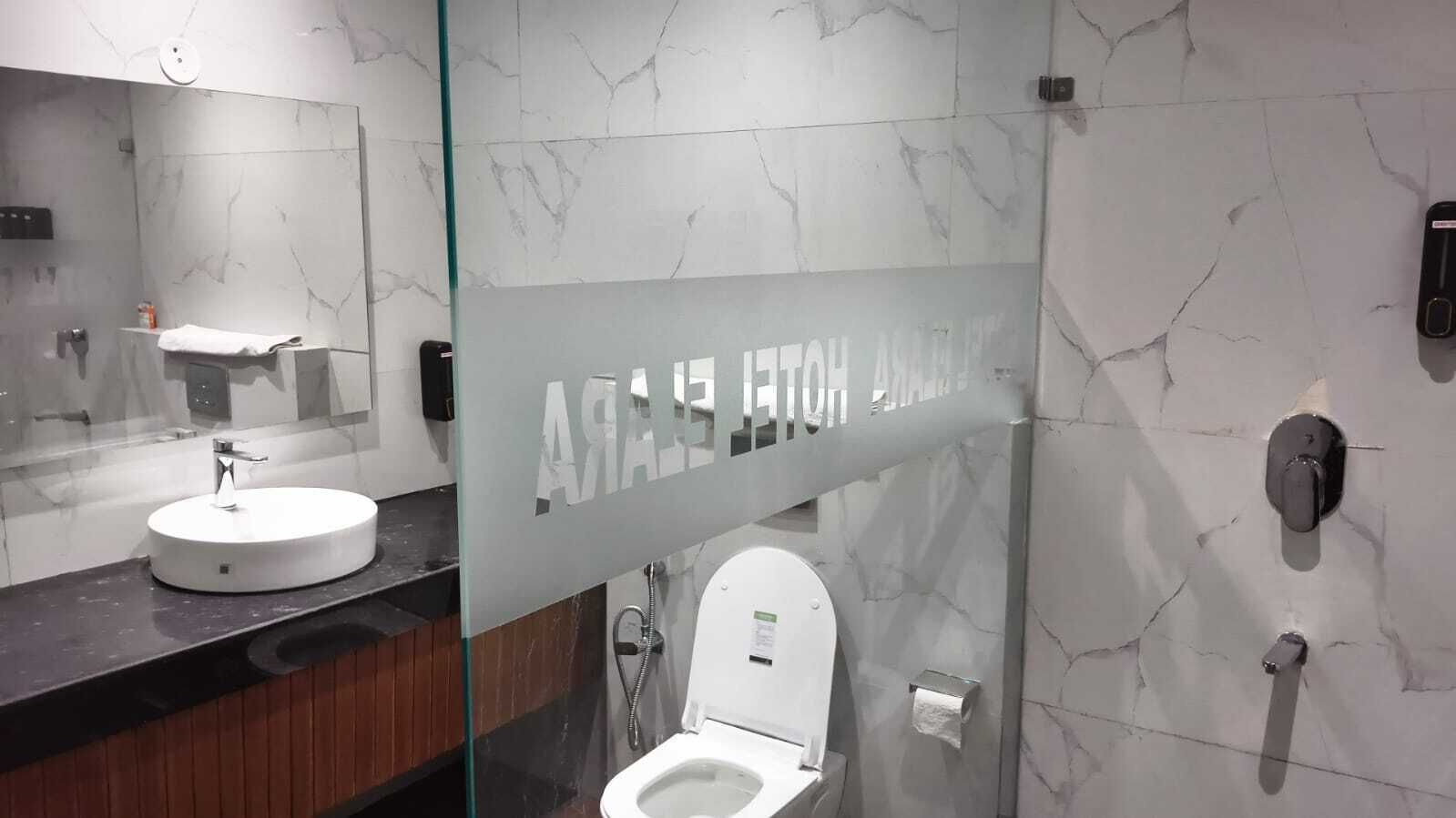 A modern bathroom with a marble wall, a round sink, and a toilet.
