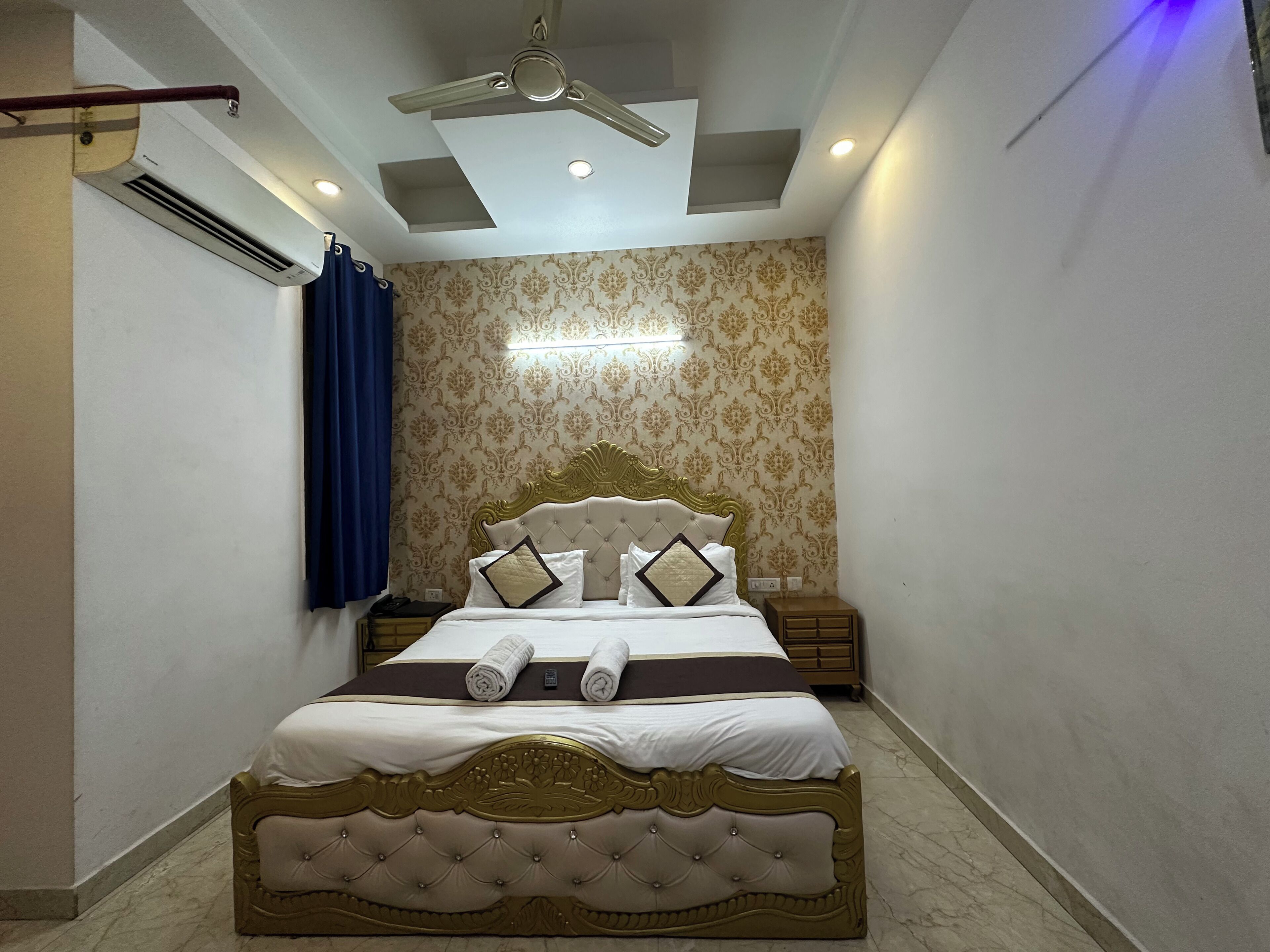 Une chambre à coucher avec un grand lit, un ventilateur de plafond, un appareil de climatisation et un papier peint à motifs.