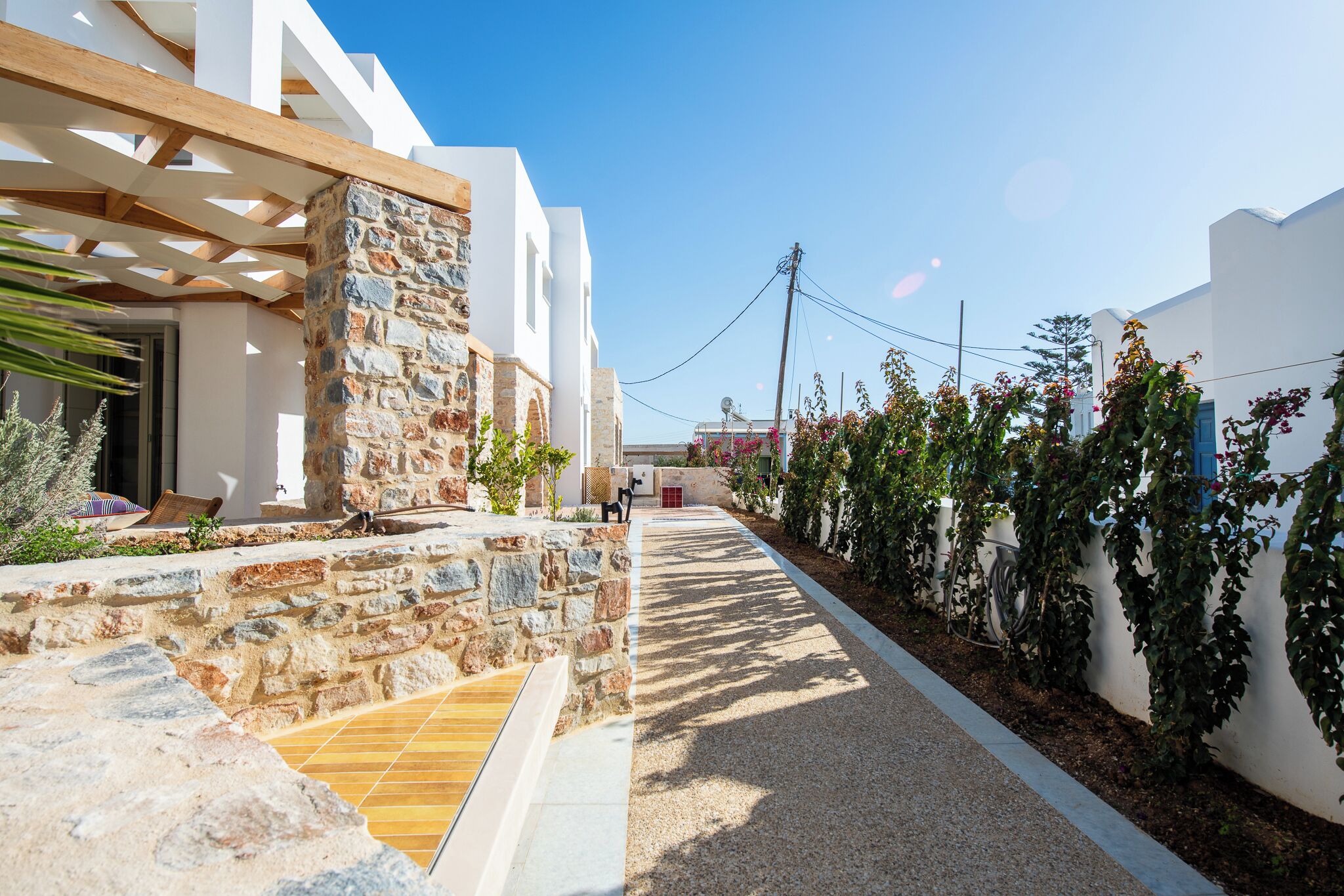 A modern building with a stone facade, a wooden pergola, and a gravel pathway.