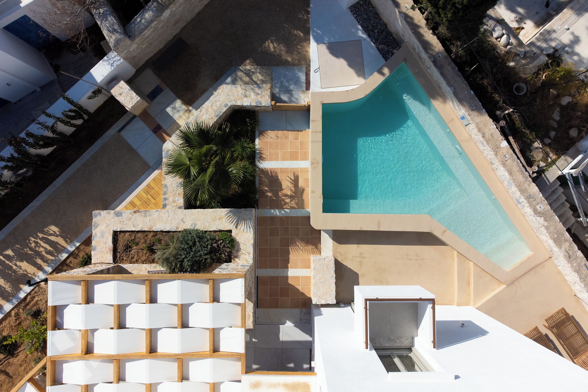 An aerial view of a hotel with a swimming pool, outdoor seating, and a landscaped garden area.