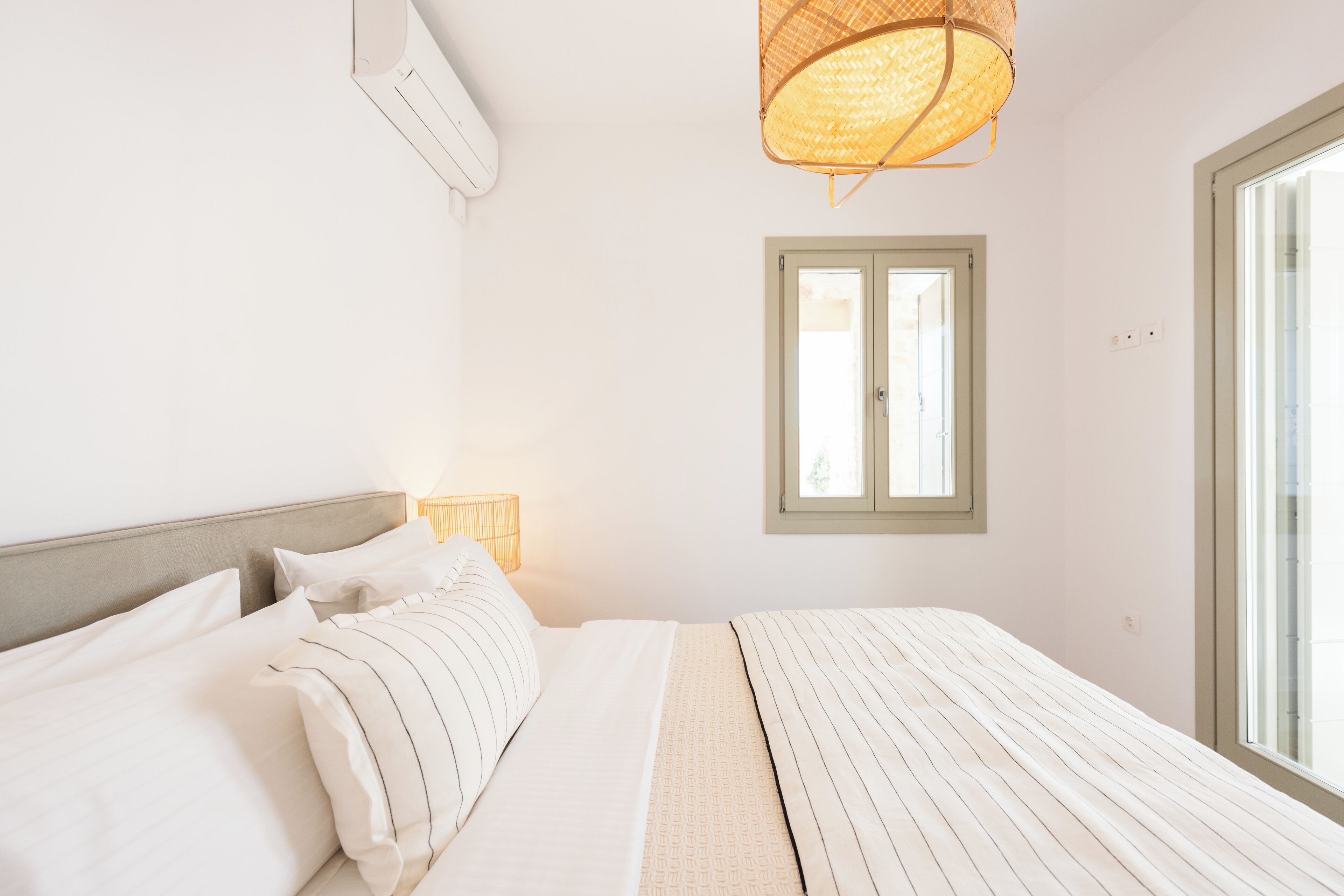 A bedroom with a bed, a window, and a wall-mounted air conditioner.