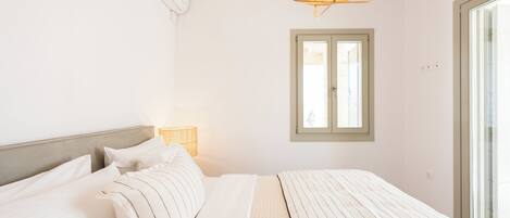 A bedroom with a bed, a window, and a wall-mounted air conditioner.