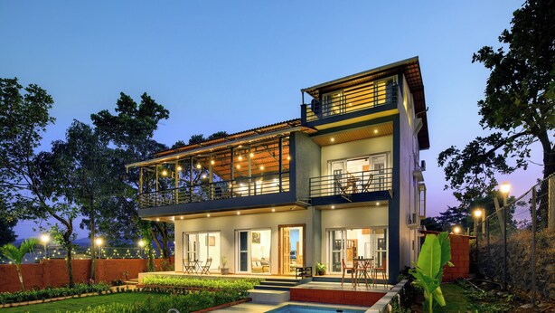 A modern two-story house with a swimming pool, large windows, and outdoor lighting. - Villa Vanakothi by Westbay (Shahuwadi)