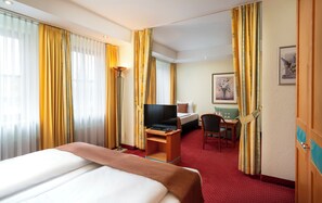 A hotel room with a bed, a desk with a computer, a chair, and a TV. - ARKADEN Hotel Kelkheim (Kelkheim)