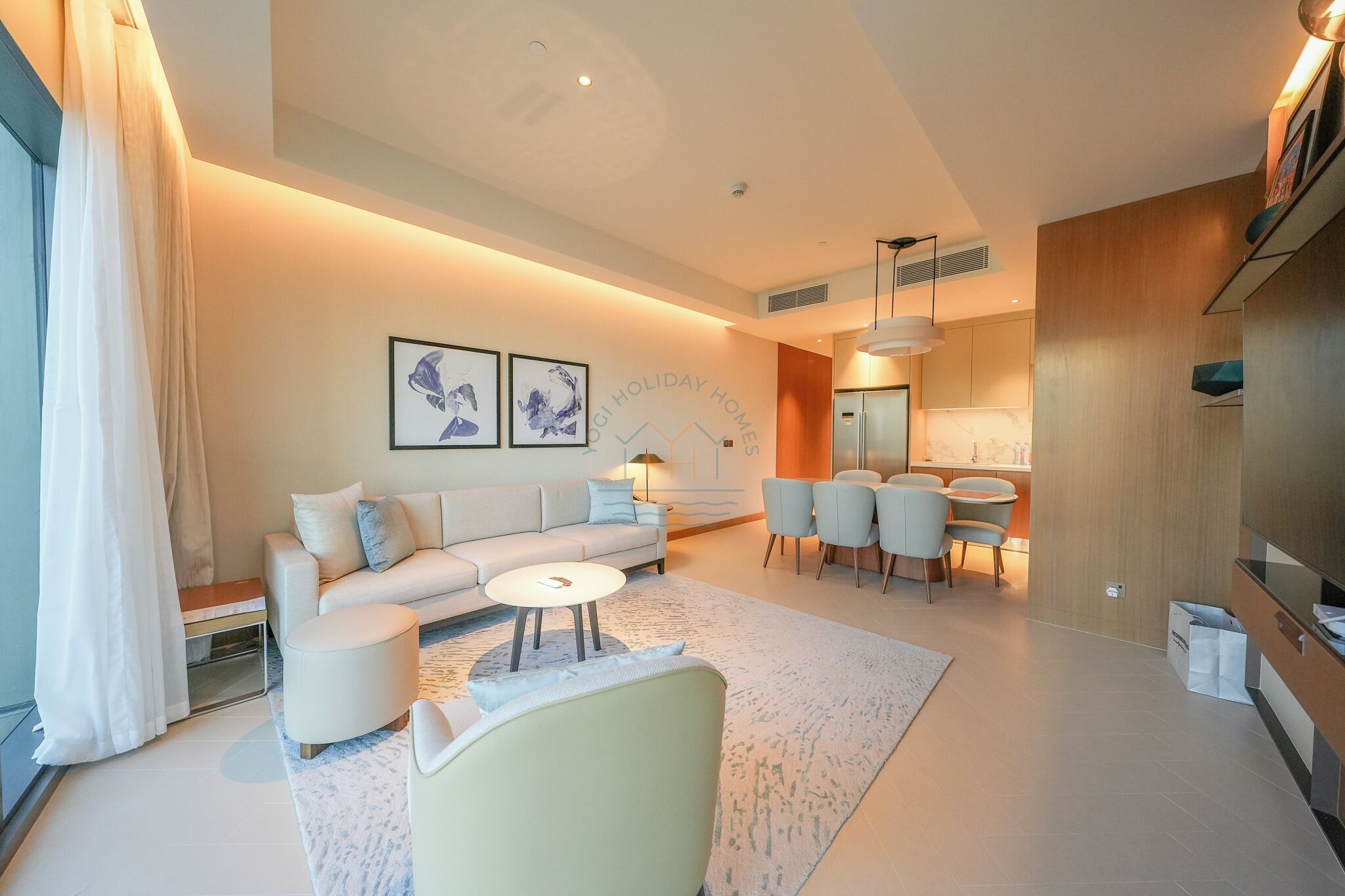 Un salon moderne comprenant un canapé, des fauteuils, une table basse et un coin repas.