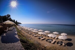 A beach with sun loungers and umbrellas, a wooden deck with chairs, and a view of the sea. - Crown Hotel  (Kassandra)