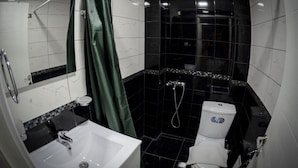 A compact bathroom with a white sink, a toilet, and a shower area. - Crown Hotel  (Kassandra)