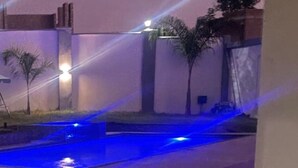 A pool area with a blue-lit water feature, surrounded by a low wall and palm trees. - Gletwyn House Retreat in Harare (Harare)