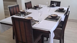 A rectangular dining table with a white tablecloth, surrounded by dark wooden chairs. - Gletwyn House Retreat in Harare (Harare)
