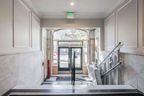 A hotel entrance with a marble floor, a glass door with a sign, and a metal staircase. - 18BR 17BA Combined Apartments close to Lucas Oil Stadiom (Indianapolis)