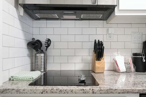 Une cuisine avec des murs recouverts de carreaux blancs, un évier en acier inoxydable et un plan de travail en granit.
