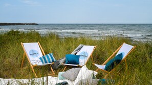 Relax in comfort with a beachside setup featuring three chairs, each with a cushion and table.
